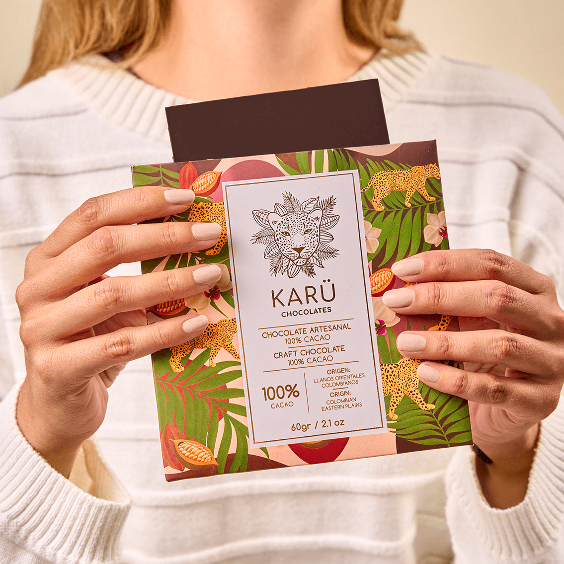 Young woman out of focus holding a Karü 100% cacao chocolate bar, highlighting the artisanal packaging and Colombian origin.