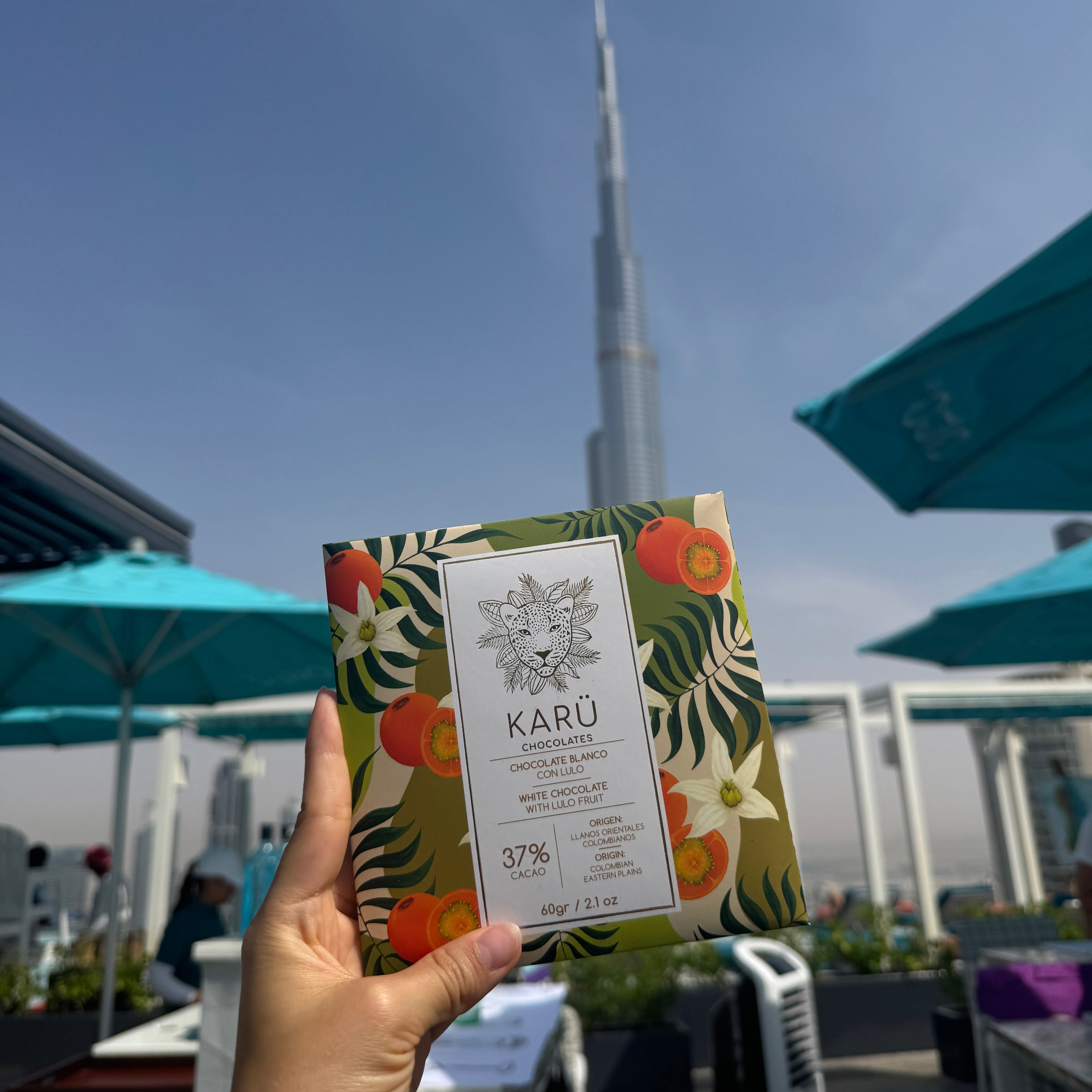 Hand holding a Karu chocolate bar with a cityscape in the background