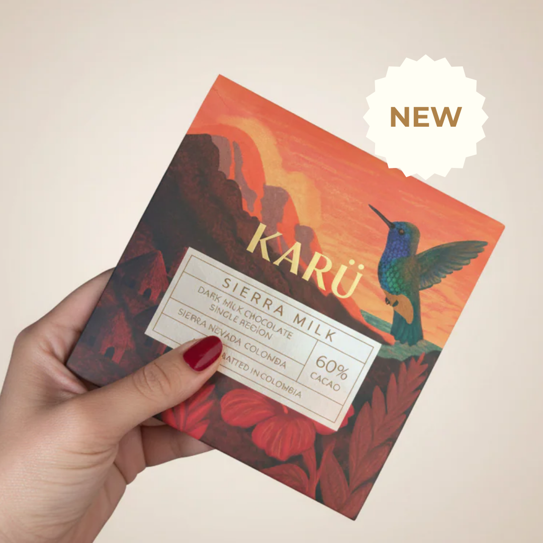 Hand holding a Sierra Milk Karu chocolate bar with a colorful landscape and 'NEW' label.